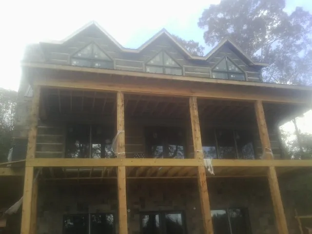 Dormers and porch framing on a large log home under construction — Roof Coating work by our crew in Hinsdale