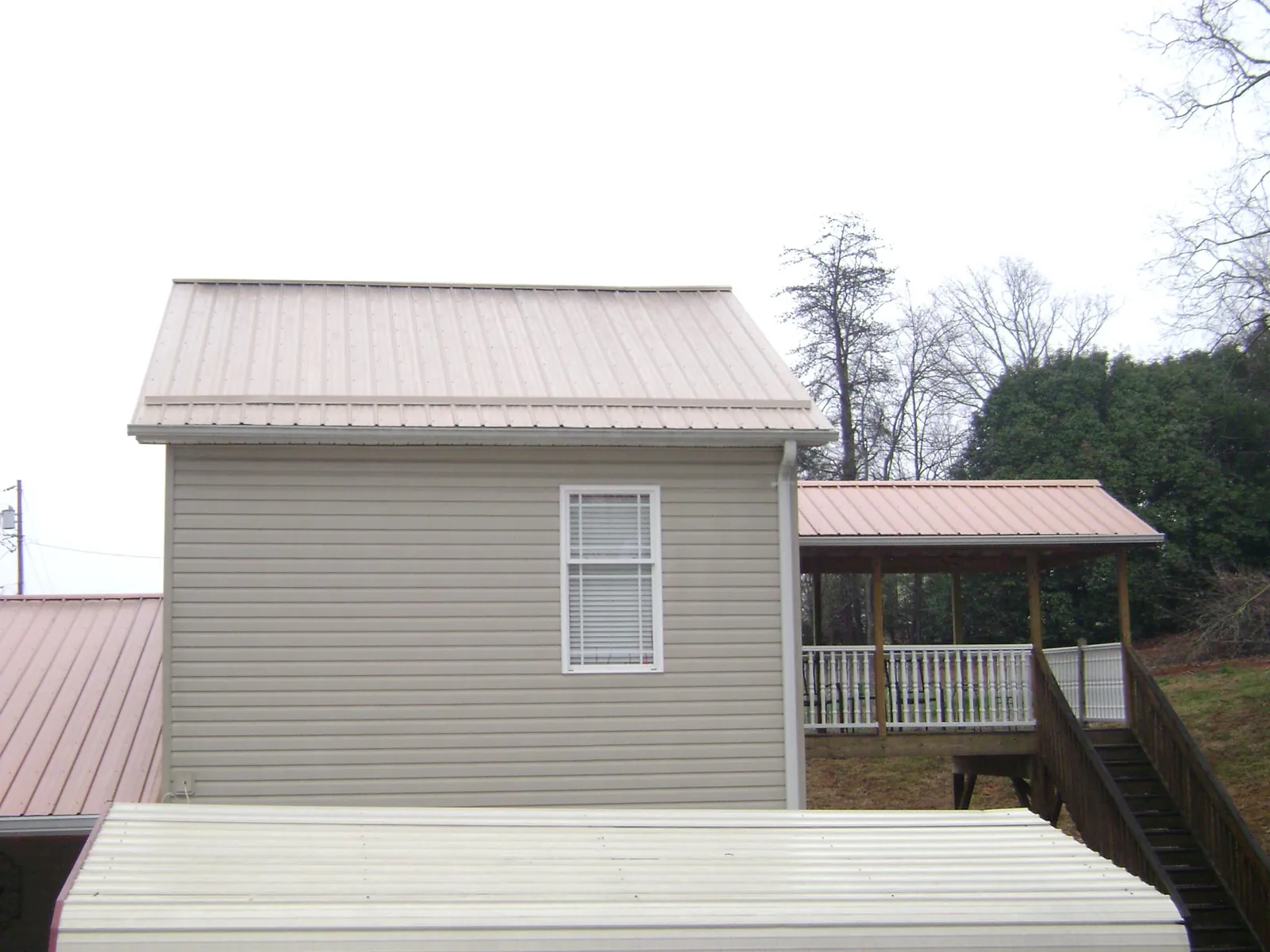 Tan metal roofs on a two story addition and attached porch, from a Roof Replacement job in Hinsdale