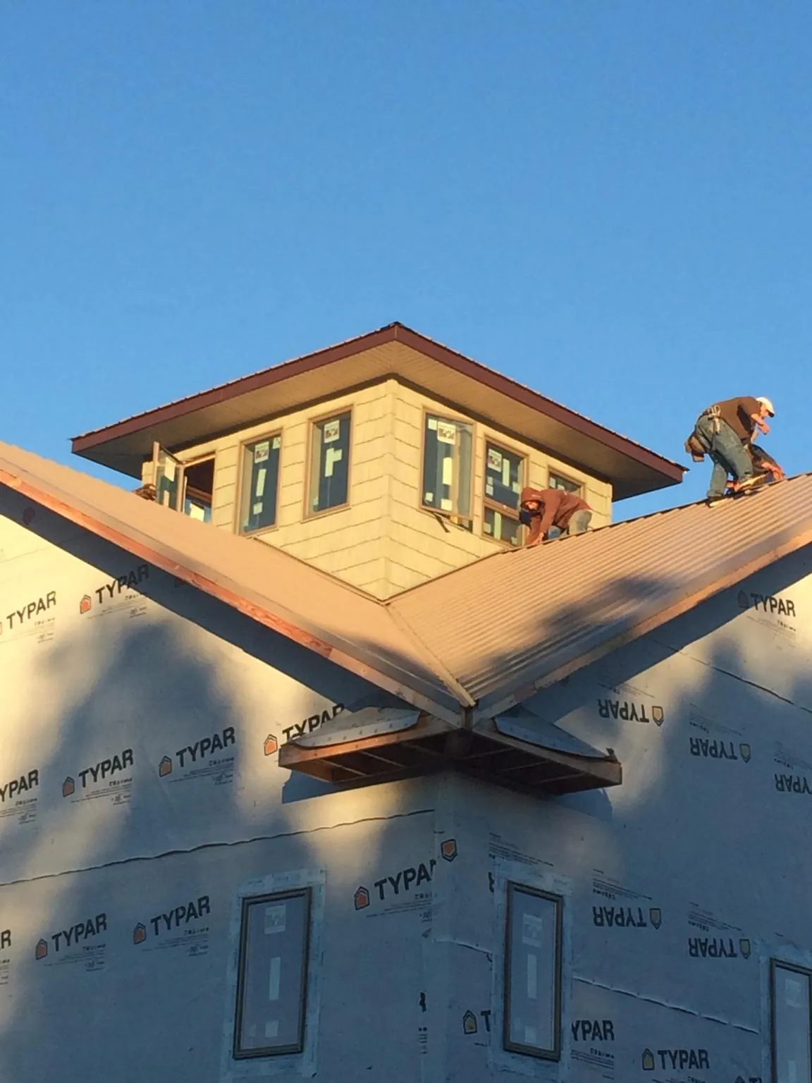 Roofers working around a rooftop cupola on a new metal roof at sunset — Roof Waterproofing in Hinsdale by Roofing Brothers